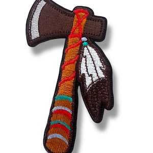 Puede incluir: Parche bordado con forma de tomahawk con una pluma. La cabeza del hacha es marrón con costuras blancas, el mango es marrón y naranja con detalles rojos, azules y plateados. Se adjunta una pluma blanca y marrón.