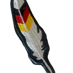 May include: Embroidered feather patch with a black border. The feather features a silver-grey design with a section of red, black, and yellow, resembling a flag. This patch is suitable for jackets, bags, or other fabric items.