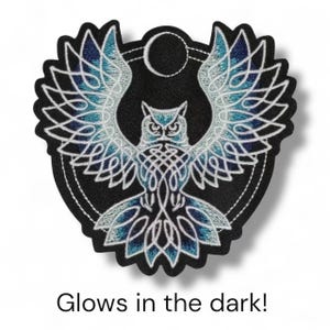 May include: Embroidered patch featuring an owl with outstretched wings, detailed with white and blue knotwork on a black background. The design includes a moon and the text "Glows in the dark!"