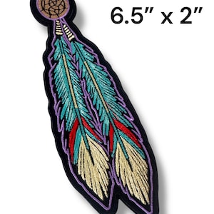 May include: Embroidered patch featuring a dreamcatcher design with two feathers. The feathers are teal, red, and gold, outlined in purple and black. The patch measures 6.5 inches by 2 inches.