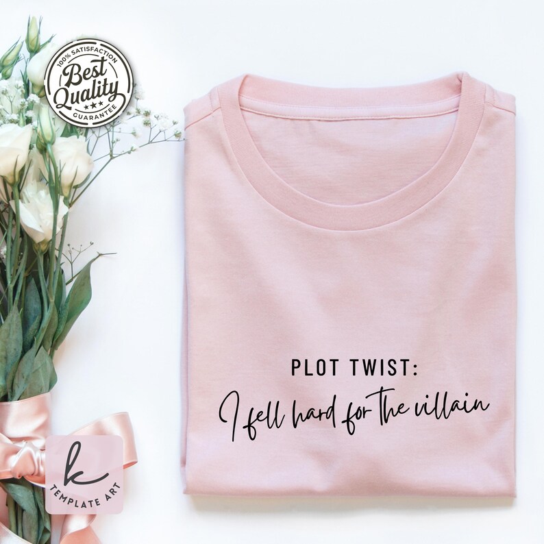 K&ouml;nnte beinhalten: Ein hellrosa T-Shirt mit dem schwarzen Schriftzug "PLOT TWIST: I fell hard for the villain". Das T-Shirt ist sauber gefaltet. Ein "Best Quality Guarantee" Aufkleber ist oben links zu sehen.