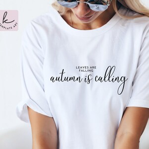 Könnte beinhalten: Weißes T-Shirt mit dem Text "Leaves are falling, autumn is calling" in schwarzer Schrift.