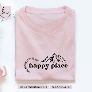 May include: A pink t-shirt with a black graphic design of mountains and the text "The mountain is my happy place".