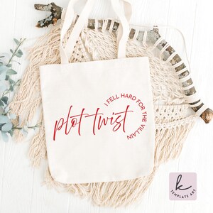 Op de afbeelding: Een witte canvas draagtas met rode tekst die "plot twist" leest in een cursief lettertype, met de zin "I fell hard for the villain" in een cirkelvormig lettertype eromheen. De tas heeft twee handvatten en wordt op een neutrale achtergrond gepresenteerd.