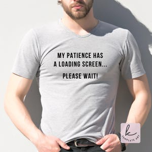 May include: A light gray V-neck t-shirt with the text "MY PATIENCE HAS A LOADING SCREEN... PLEASE WAIT!" printed in black. The shirt is worn by a person.