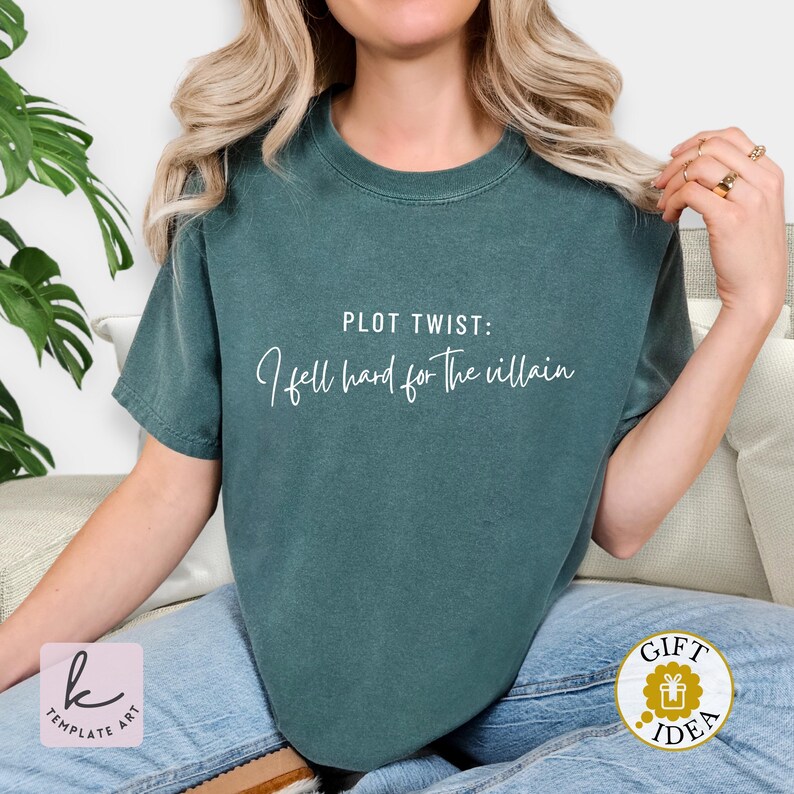 K&ouml;nnte beinhalten: Dunkelgr&uuml;nes T-Shirt mit dem wei&szlig;en Schriftzug "PLOT TWIST: I fell hard for the villain". Das Shirt ist einfarbig und hat kurze &Auml;rmel. Ein Geschenkideen-Aufkleber ist unten rechts sichtbar.