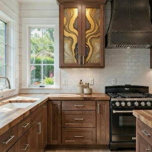 May include: A kitchen with dark wood cabinetry and countertops. The upper cabinets have glass doors with a gold and black abstract design. A black range and hood are visible, along with a white tile backsplash and hardwood flooring.