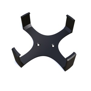 May include: Black plastic wall mount with four arms designed to hold a round object, such as a speaker or a bottle.
