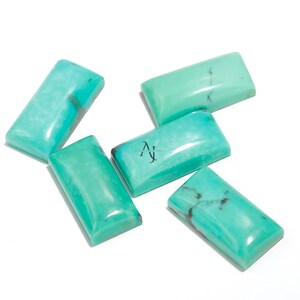 Op de afbeelding: Vijf turquoise cabochon edelstenen in een rechthoekige vorm. De stenen zijn lichtblauwgroen van kleur met wat donkerdere aderen die er doorheen lopen.