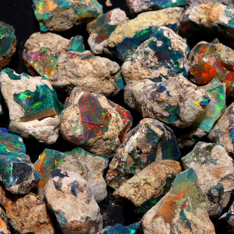 A close-up shot of rough Ethiopian opal chunks featuring vibrant orange, red, and green play of color.