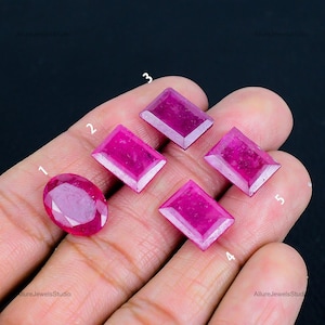 Op de afbeelding: Vijf roze robijn edelstenen in verschillende vormen en maten, genummerd van 1 tot 5.