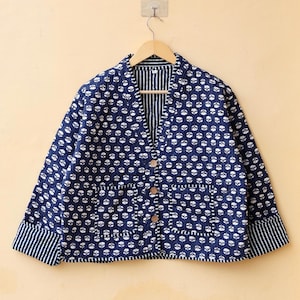 May include: A navy blue quilted jacket with a white floral print and striped cuffs. The jacket has a V-neck and a button closure.