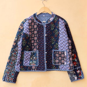 May include: A blue quilted jacket with a floral print and a button closure. The jacket has two pockets and a white and blue striped lining.