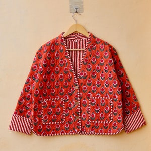 May include: A red quilted jacket with a floral print and a button fastening. The jacket has a striped lining and two pockets.