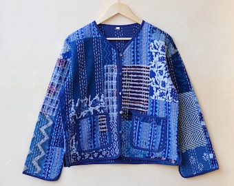 Può includere: Una giacca trapuntata blu con un design a patchwork e chiusura con bottoni. La giacca ha una tasca su ogni lato.