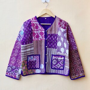 May include: A purple quilted jacket with a patchwork design. The jacket has a button closure and two pockets.