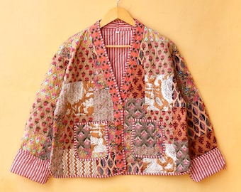 Könnte beinhalten: Eine Patchwork-Steppjacke mit V-Ausschnitt, langen Ärmeln und Knopfleiste. Die Jacke besteht aus verschiedenen Stoffen in Braun-, Rosa- und Weißtönen mit floralen und geometrischen Mustern.