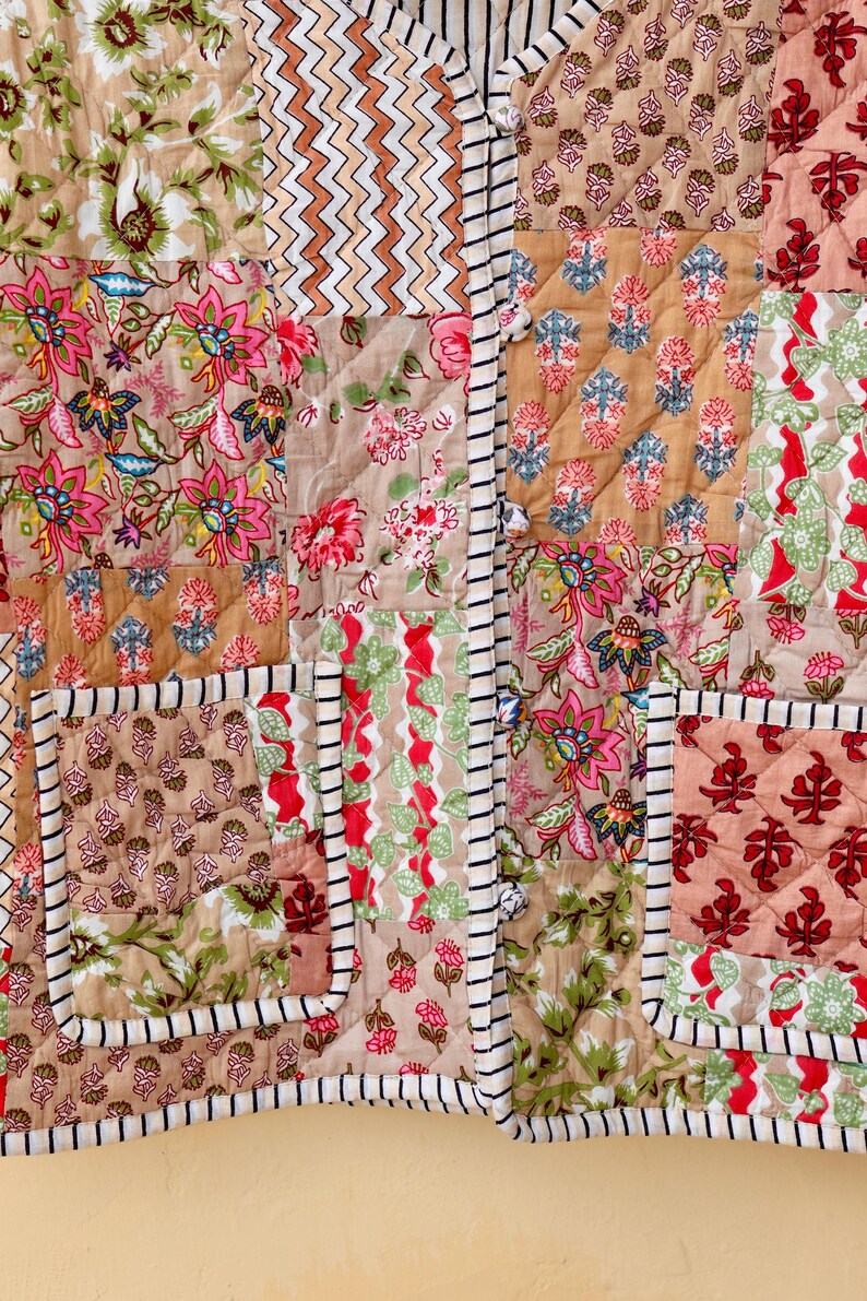May include: A patchwork quilt with a variety of floral patterns in shades of pink, green, and brown. The quilt is quilted with a diamond pattern and has a white and black striped border.