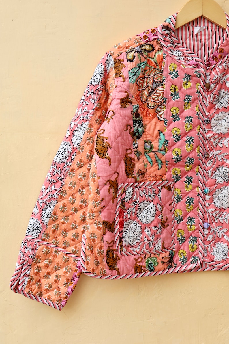 Op de afbeelding: Gewatteerde patchworkjas met bloemen- en tijgerprints in roze, perzik en wit. De jas heeft een kraag, knoopsluitingen en een zak. Afmetingen in centimeters.