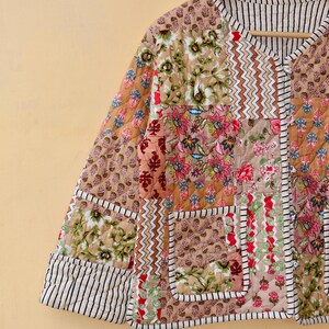 May include: A quilted jacket with a patchwork design featuring floral and geometric patterns in shades of brown, pink, and green. The jacket has a V-neck and a button closure.
