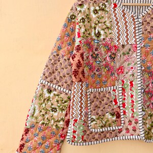 May include: A brown quilted jacket with a patchwork design featuring floral and geometric patterns. The jacket has a V-neck and a button closure.