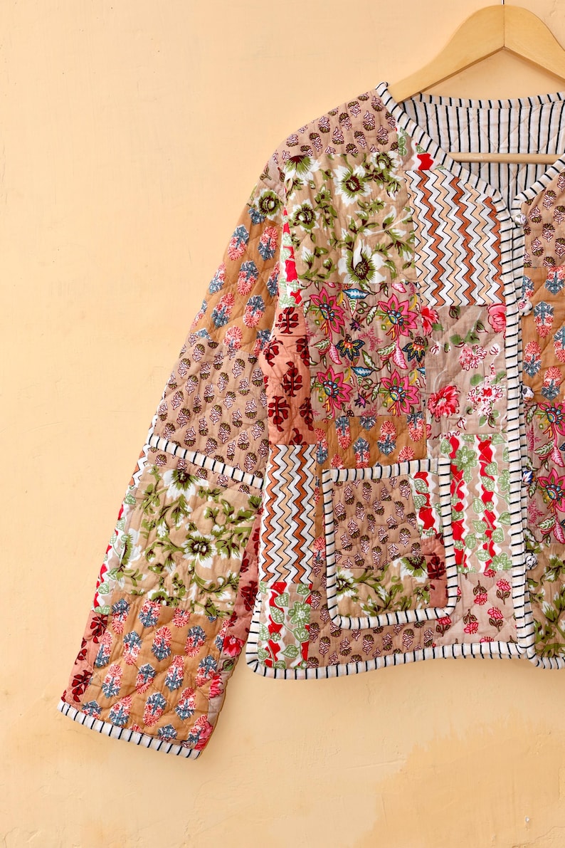 May include: A brown quilted jacket with a patchwork design featuring floral and geometric patterns. The jacket has a V-neck and a button closure.