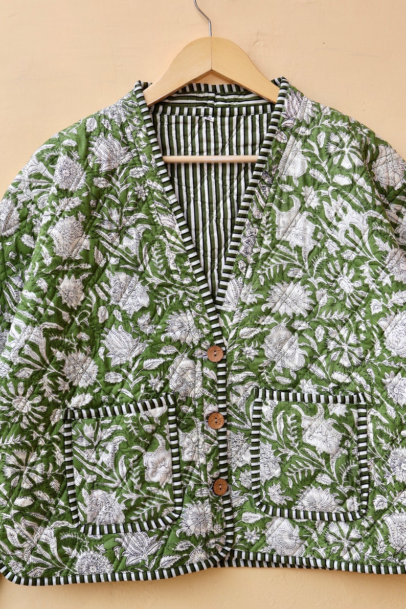 Puede incluir: Una chaqueta acolchada verde con estampado floral blanco y forro a rayas. La chaqueta tiene cierre de bot&oacute;n y dos bolsillos.