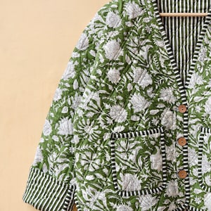 Puede incluir: Una chaqueta acolchada verde con estampado floral blanco y forro a rayas. La chaqueta tiene cierre de bot&oacute;n y un bolsillo en el lado izquierdo.