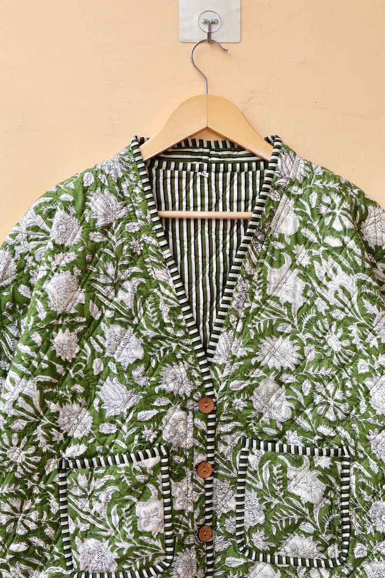 Puede incluir: Una chaqueta acolchada verde con estampado floral blanco y forro a rayas. La chaqueta tiene cuello en V, cierre de bot&oacute;n y dos bolsillos de parche.