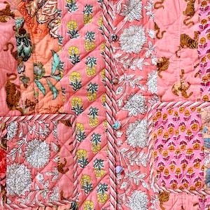 Op de afbeelding: Gewatteerde jas met een patchwork ontwerp met bloemen- en tijgerprints in roze, perzik en wit. De jas heeft een knoopsluiting en twee zakken. De algehele esthetiek is boheems en artistiek.