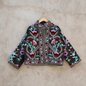 Peut inclure: Une veste en velours gris fonc&eacute; avec des broderies florales color&eacute;es. La veste a un col mandarin et des manches longues.