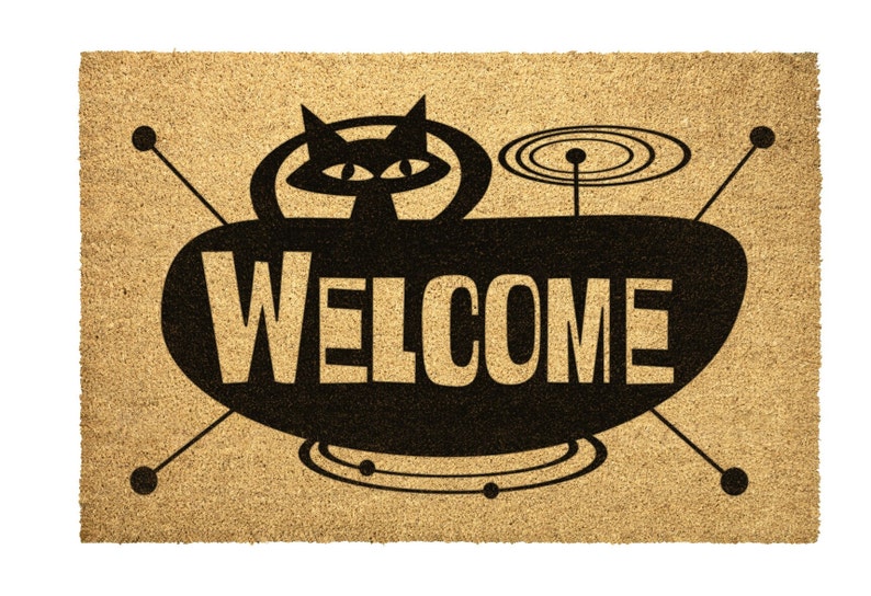 May include: A brown coir doormat with a black silhouette of a cat in a flying saucer with the word "WELCOME" printed on the saucer.