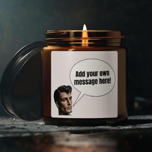 May include: A brown glass candle jar with a lit wick and a black lid placed to the side. The white label features a graphic of a person's head in profile next to a speech bubble containing the black text, Add your own message here!