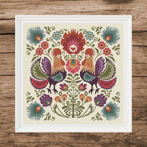 Può includere: Uno schema di punto croce con due galli dal piumaggio colorato, circondati da un motivo floreale con fiori rossi, rosa, verdi e blu. Lo schema è incorniciato in una cornice bianca.