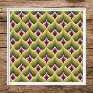 May include: A framed cross-stitch pattern featuring a repeating design of stylized green and yellow leaves with a central dark pink diamond shape. The artwork is set against a wooden background.