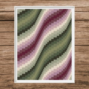 May include: A framed abstract art print featuring a pixelated design with wavy lines. The artwork uses a palette of green, purple, and cream colors. The print is in a white frame, set against a wooden background.
