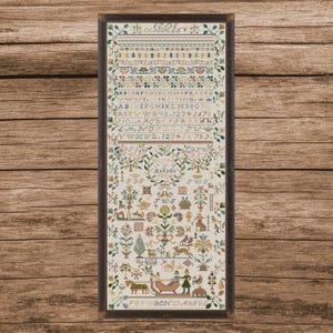 May include: Framed antique sampler with detailed cross-stitch embroidery. The sampler features floral and geometric patterns, alphabets, numbers, and the text "EFFLE" and "Fes WDEN 23 AUSVS". The color palette includes greens, blues, and reds.