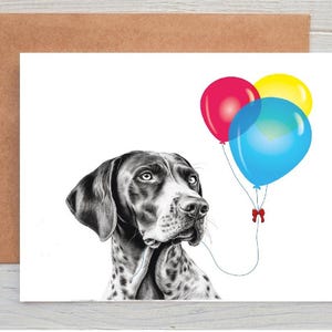 May include: A greeting card with a black and white illustration of a dog with a spotted coat. The dog is looking to the right, with three colourful balloons in the background. The balloons are red, yellow, and blue.
