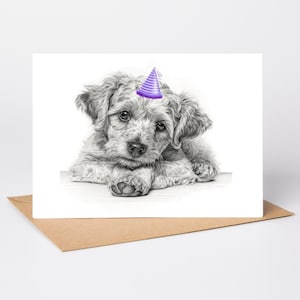 May include: A black and white pencil drawing of a puppy wearing a purple party hat. The puppy is lying down with its paws crossed, and the drawing is on a white card. The card is on a brown envelope.