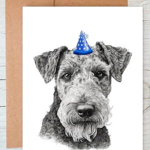 以下が含まれることがあります： 白黒の犬のイラストで、青い星柄のパーティーハットをかぶっています。犬は正面を向いています。