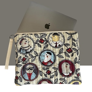 Può includere: Una custodia beige per laptop con un design a uccelli stravagante. La custodia presenta un motivo ripetuto di uccelli in cornici circolari, circondati da motivi floreali e di foglie. Un laptop grigio è parzialmente visibile all'interno.