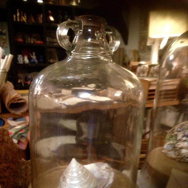 Grande cloche en verre forme bouteille sur socle en bois
