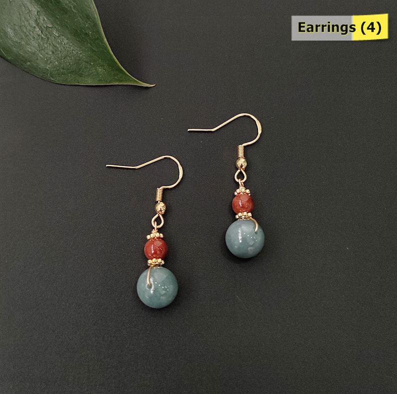 May include: A pair of gold-colored earrings with a hook design. Each earring features a small red bead, a gold-colored bead, and a larger, round, blue-green bead. The text "Earrings (4)" is in the upper right corner.