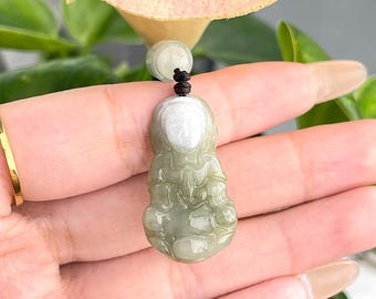May include: A green jade pendant carved in the shape of a seated figure. The pendant has a white face and is strung on a brown cord.