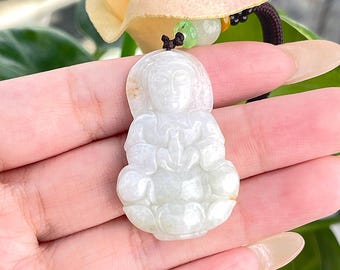 May include: White jade pendant depicting a seated figure holding a lotus flower. The pendant is on a black cord with green and brown beads.
