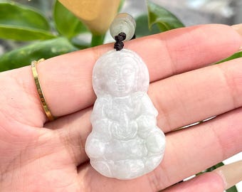 May include: A white jade pendant carved in the shape of a seated figure. The pendant is on a brown cord.