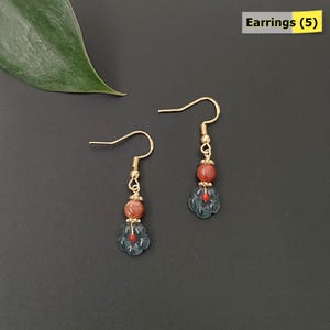 May include: A pair of gold-colored earrings with a floral design. Each earring features a gold hook, a small gold bead, a reddish-brown bead, and a blue flower-shaped bead with a red center. The text "Earrings (5)" is in the upper right corner.