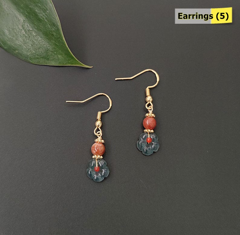 May include: A pair of gold-colored earrings with a floral design. Each earring features a gold hook, a small gold bead, a reddish-brown bead, and a blue flower-shaped bead with a red center. The text "Earrings (5)" is in the upper right corner.