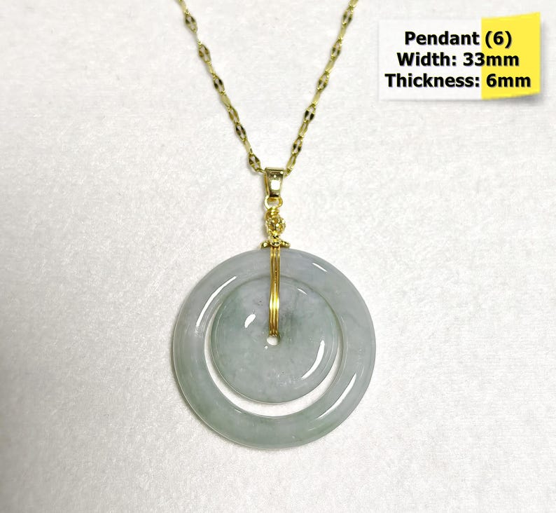 May include: A gold-colored chain necklace with a jade pendant. The pendant is a double-circle design, with a width of 33mm and a thickness of 6mm. The pendant is light green and has a gold-colored wire wrapped around it. The text "Pendant (6) Width: 33mm Thickness: 6mm" is in the image.