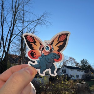 That’s the Power of Love! Adorable Chibi Mothra Carrying Godzilla Sticker - Cute Kaiju Vinyl Decal for Laptops, Water Bottles, and More